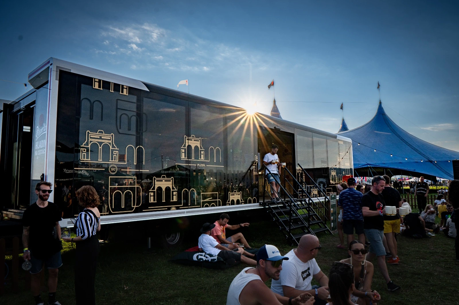Unidad promocional móvil con gráficos de cerveza en un festival soleado.
