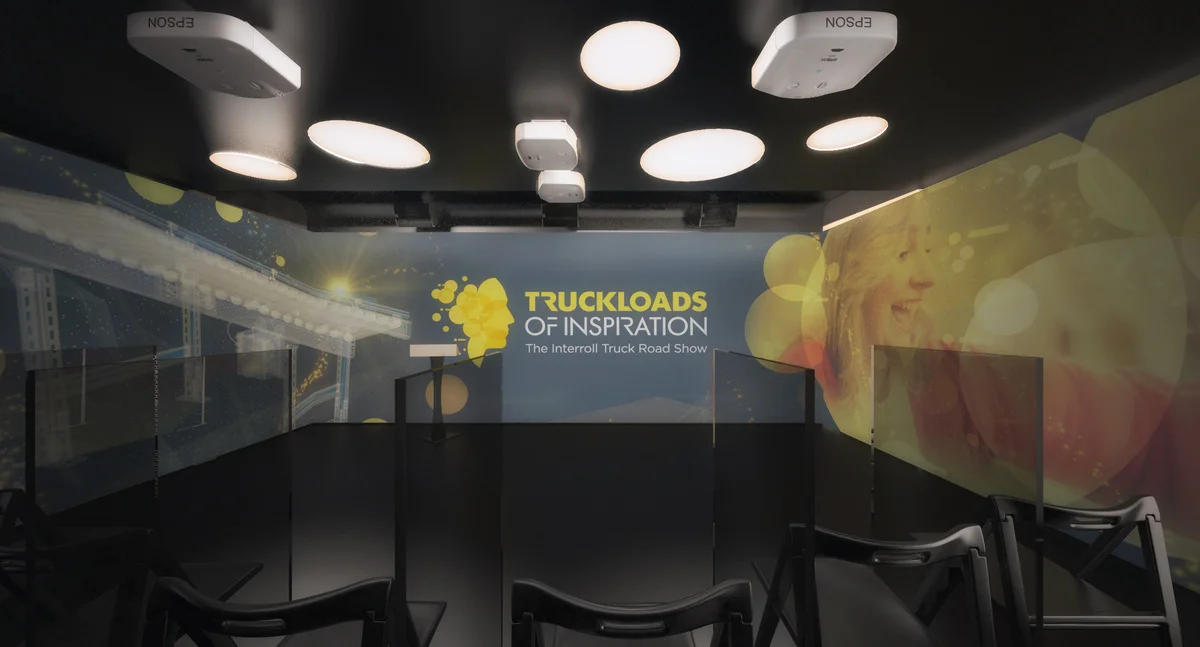Im Inneren befindet sich ein erweiterbarer, beweglicher Raum, der fĂŒr die âInterroll Truck Road Showâ eingerichtet wurde. Die Deckenbeleuchtung beleuchtet einen PrĂ€sentationsbereich mit StĂŒhlen vor einem Banner mit inspirierenden Botschaften.