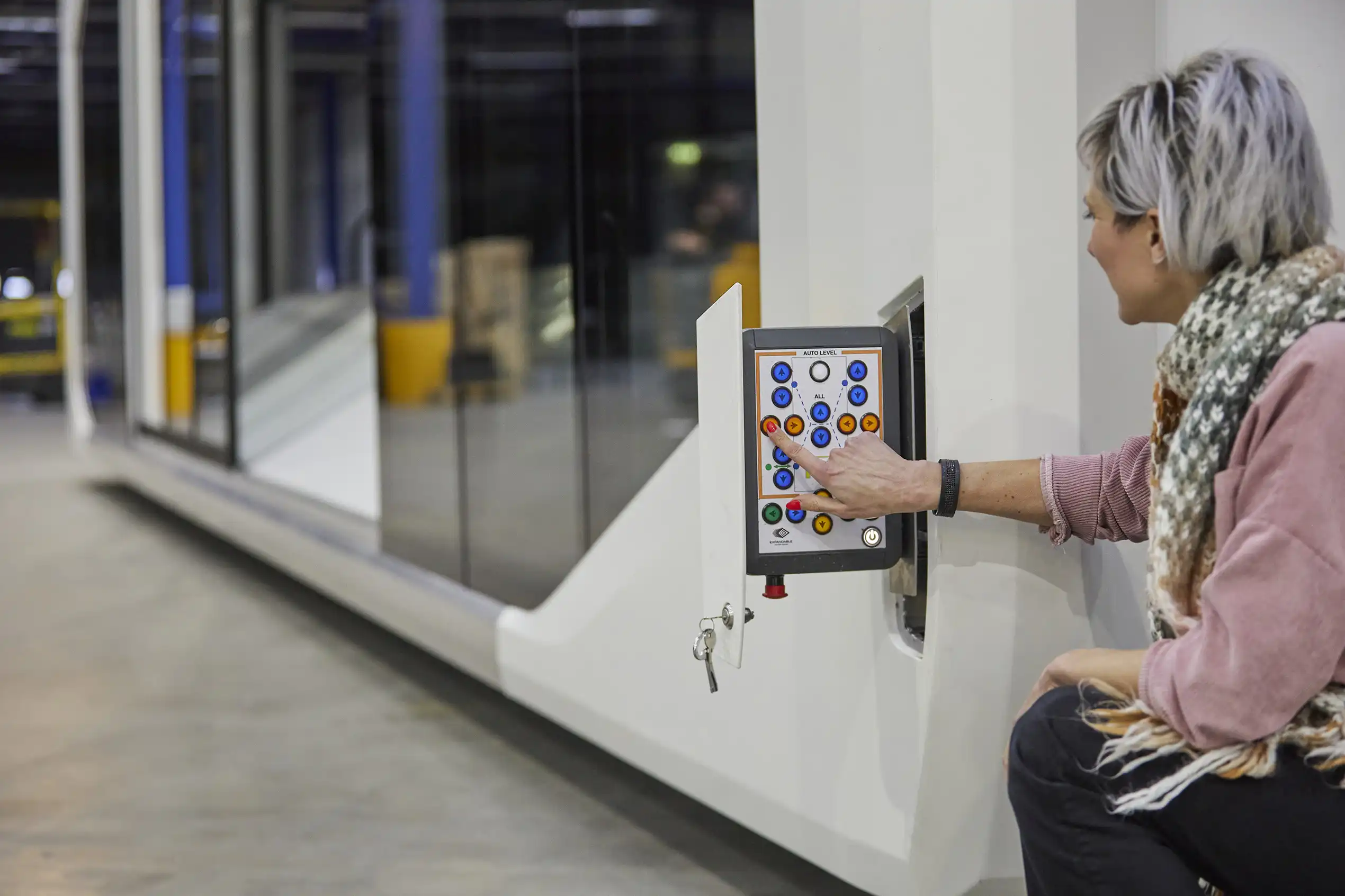 A person operates an intuitive control panel with various buttons and a key switch on an Expandable trailer, exemplifying the simplicity and functionality of the setup in an industrial environment.