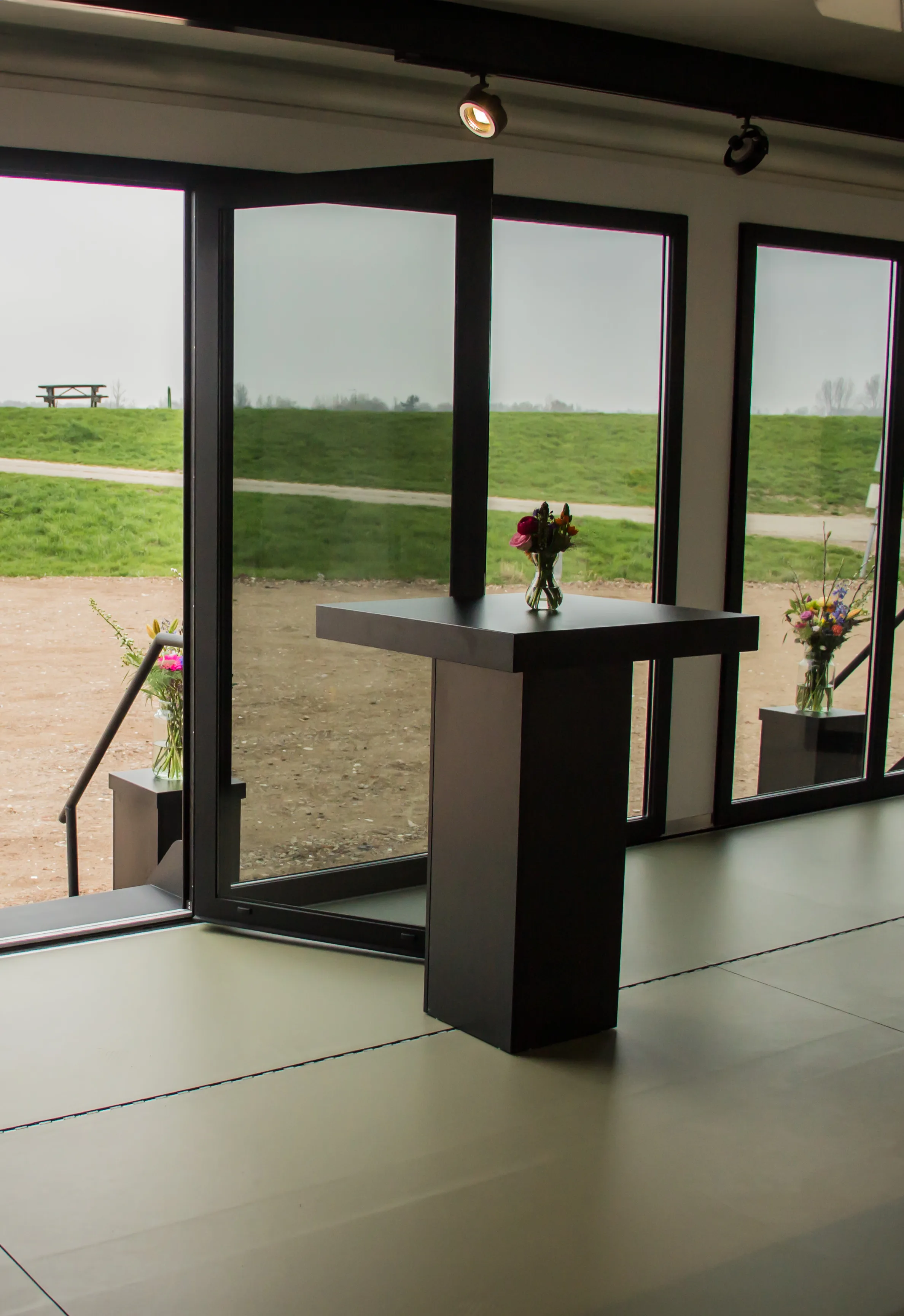 Interior view of Expandable's mobile hospitality trailer with a sleek podium and fresh flowers, large windows providing a view of the serene outdoor green landscape