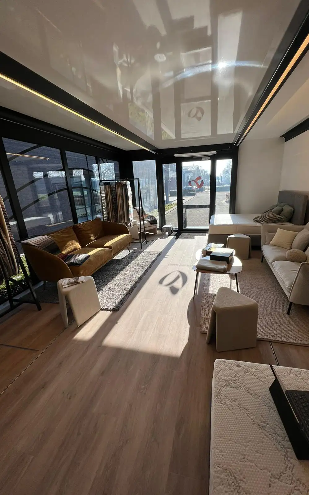 Inside the commercial trailer, a cozy and stylish lounge area with comfortable sofas, large windows, and wooden flooring