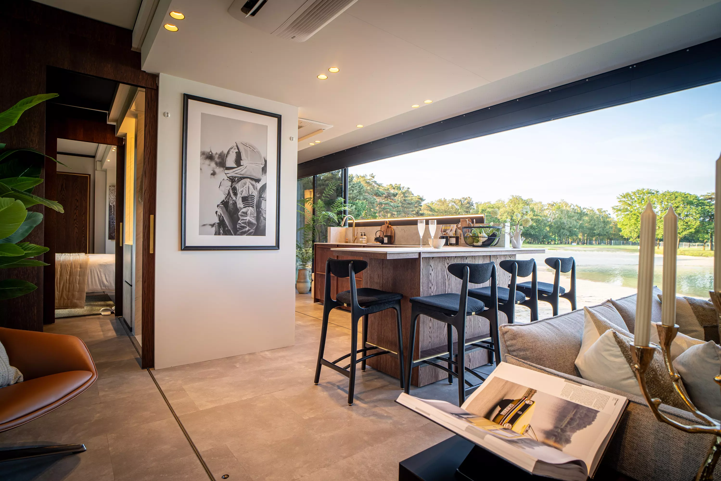 Interior view of the Expandable Mansion featuring a modern kitchen with bar seating, a cozy living area, and large windows offering a scenic outdoor view.