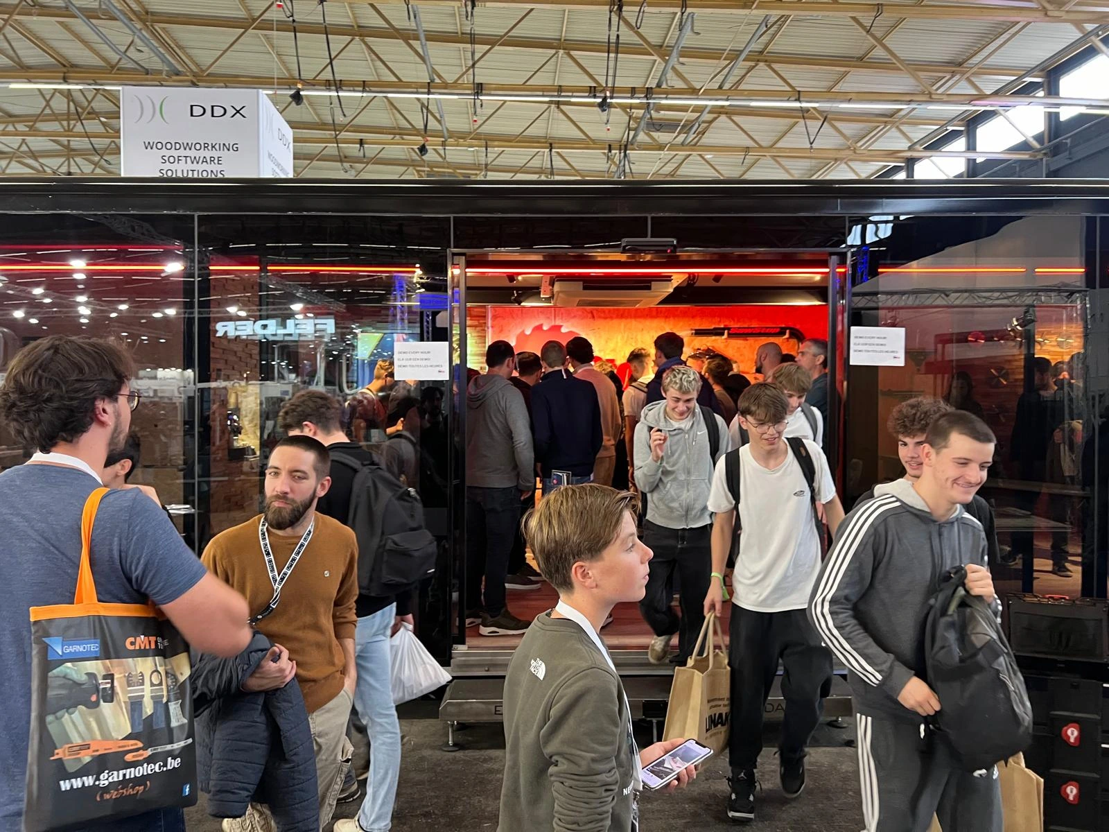 Inside a mobile workshop trailer with two technicians working on an EV battery pack at a specialized workstation, equipped with various tools and monitors displaying technical diagrams, under the branding of Autocraft.