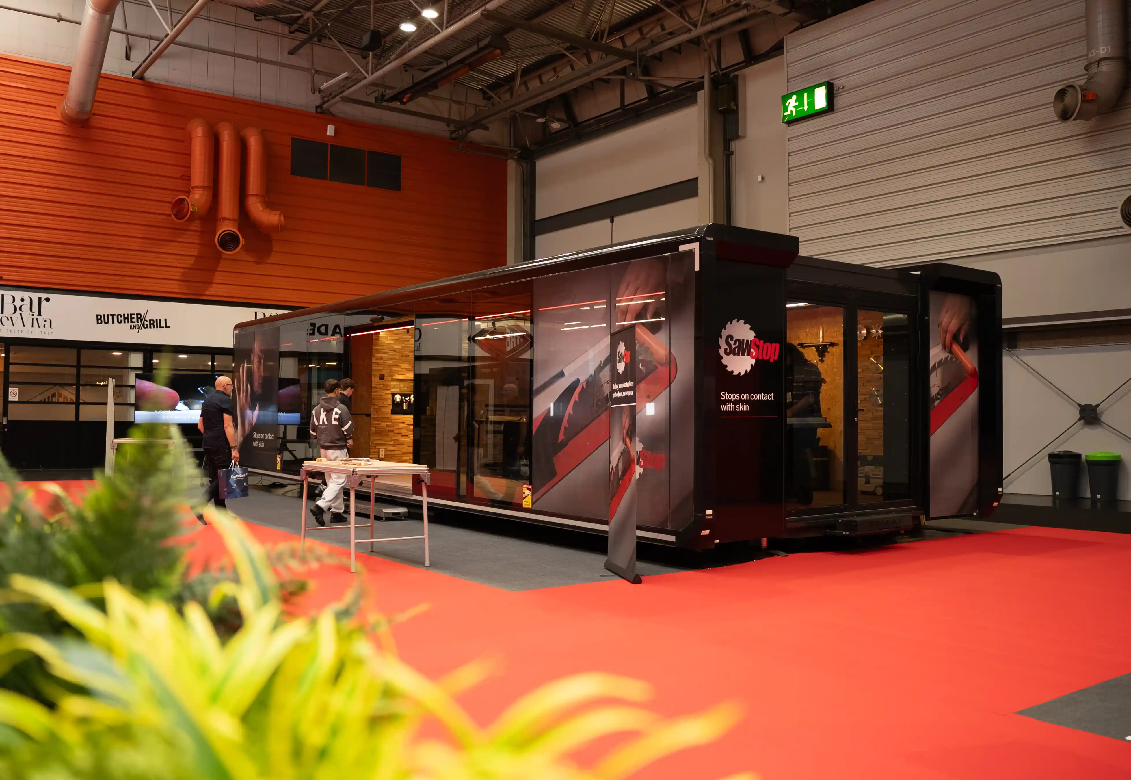 Exposición móvil ampliable de marca en una feria comercial, con plataforma retráctil en una nave industrial