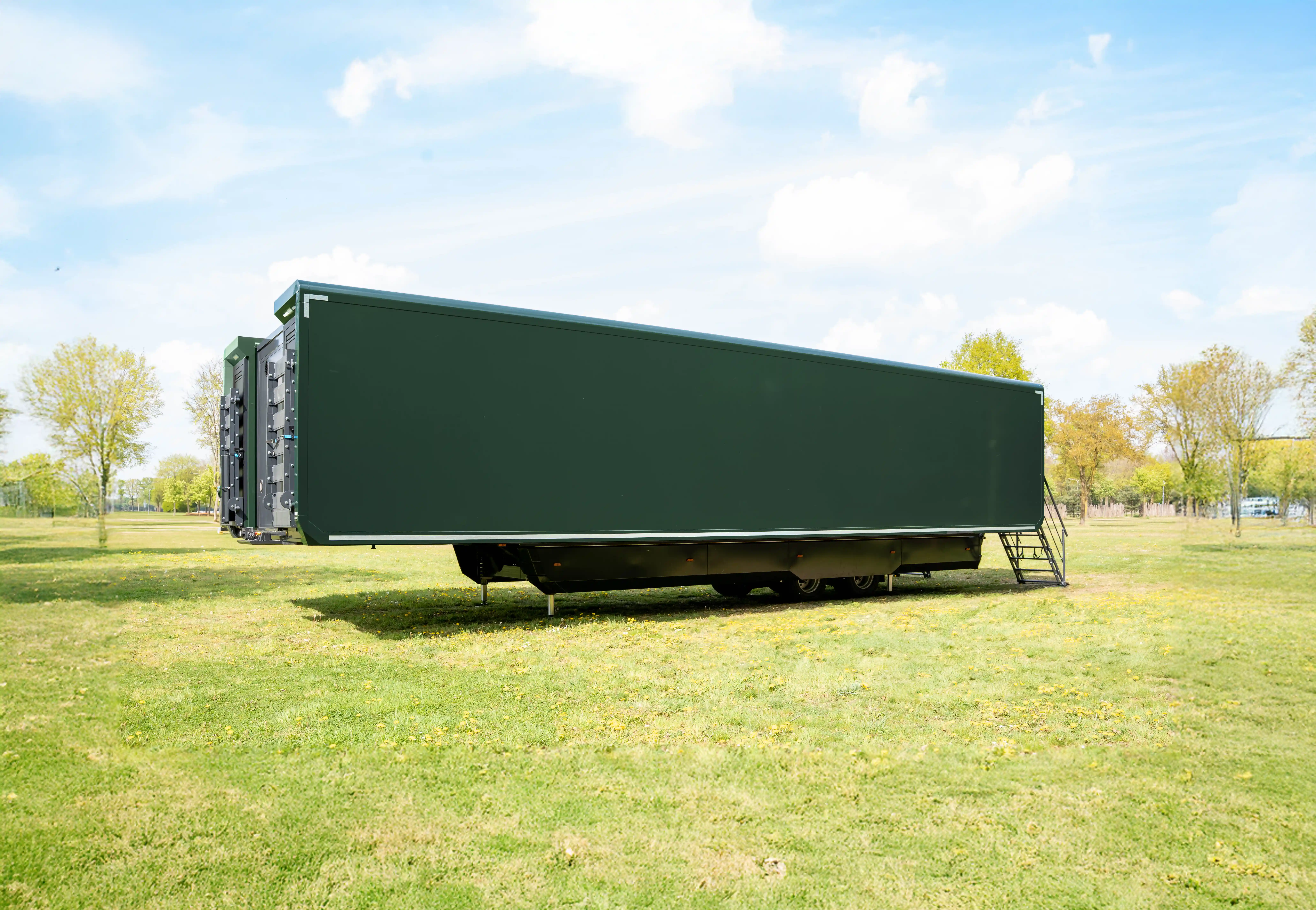 Interior of a mobile hospitality trailer transformed into a command center, equipped with multiple workstations, monitors, and blue mood lighting, with a cityscape wall graphic providing a dynamic backdrop