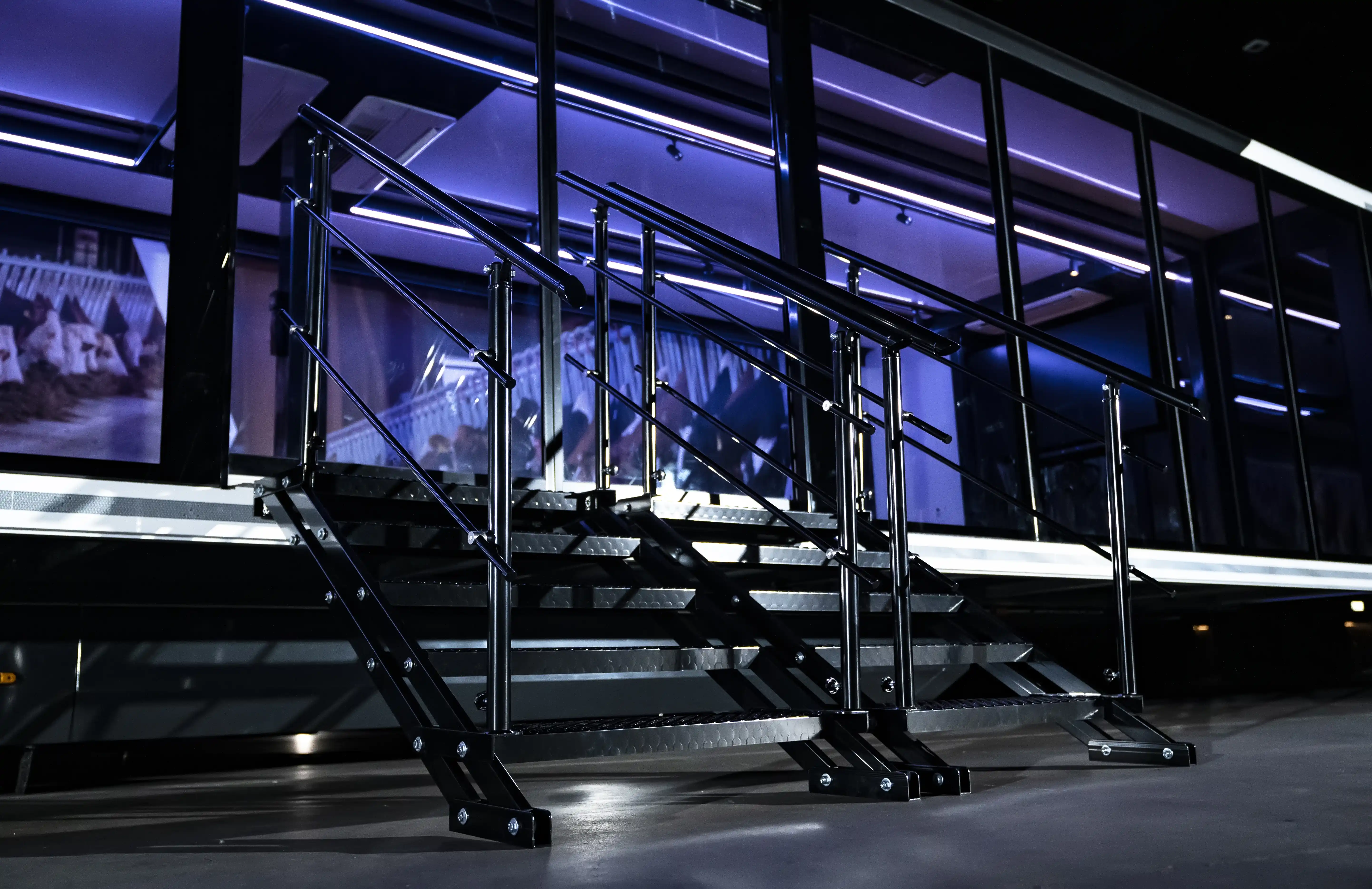 Interior of an Expandable exhibition trailer designed as an interactive seminar area with red stools, wooden tables, and informative digital displays.