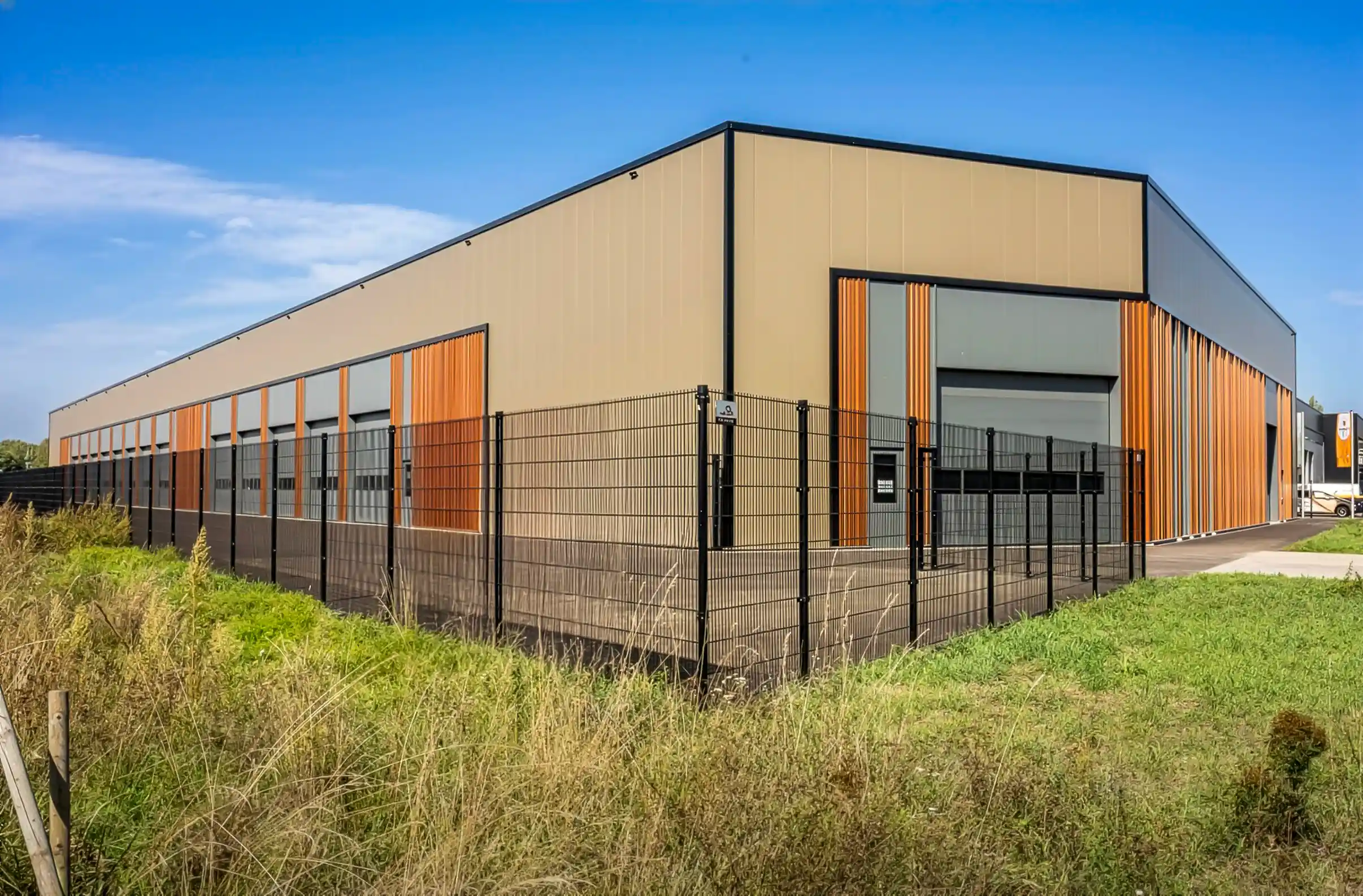 Exterior view of the new Meerheide 207 production hall with a modern facade and orange vertical accents.