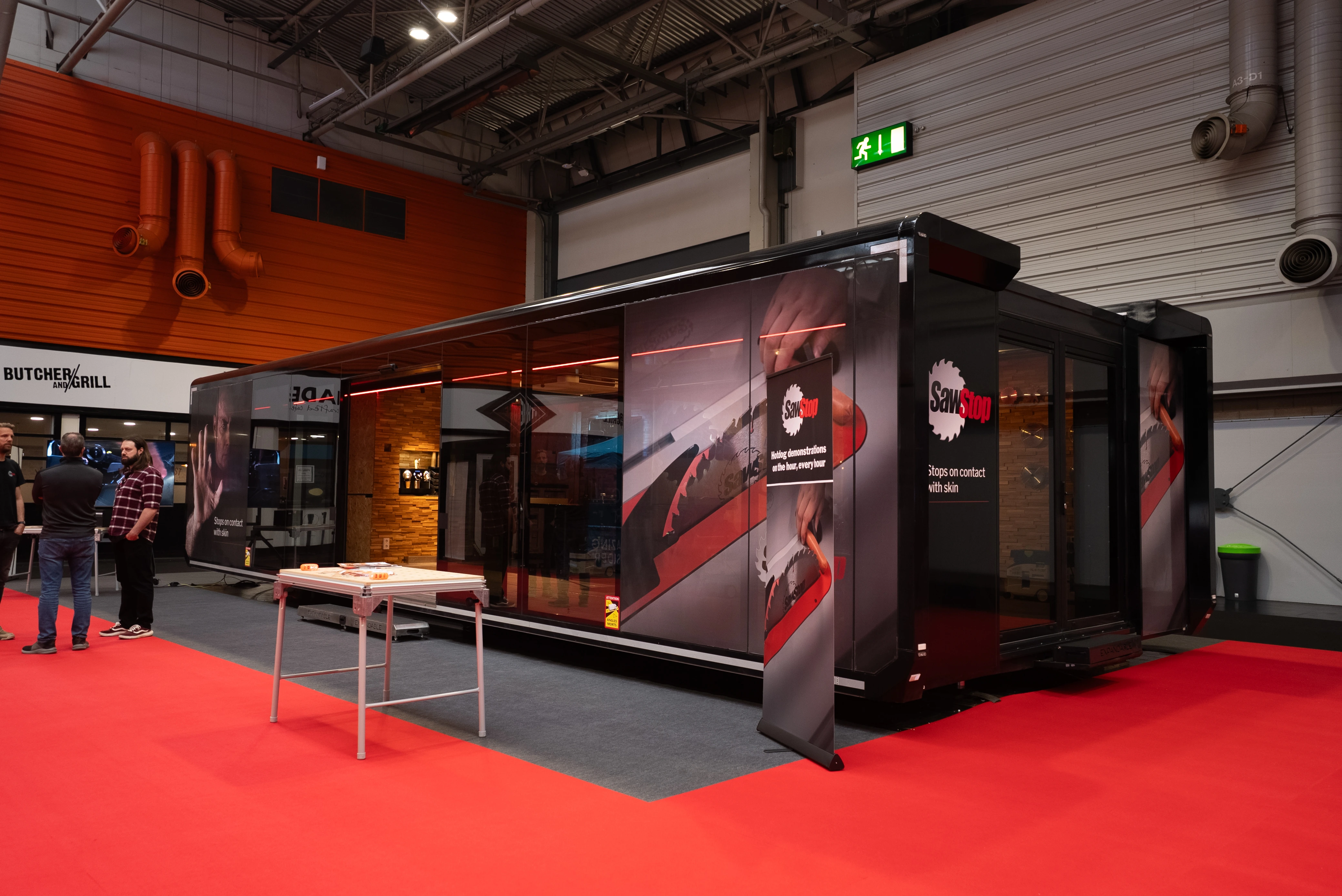Former Managing Director of SawStop Europe, standing with arms crossed in front of the fully deployed Expandable unit at a trade show.