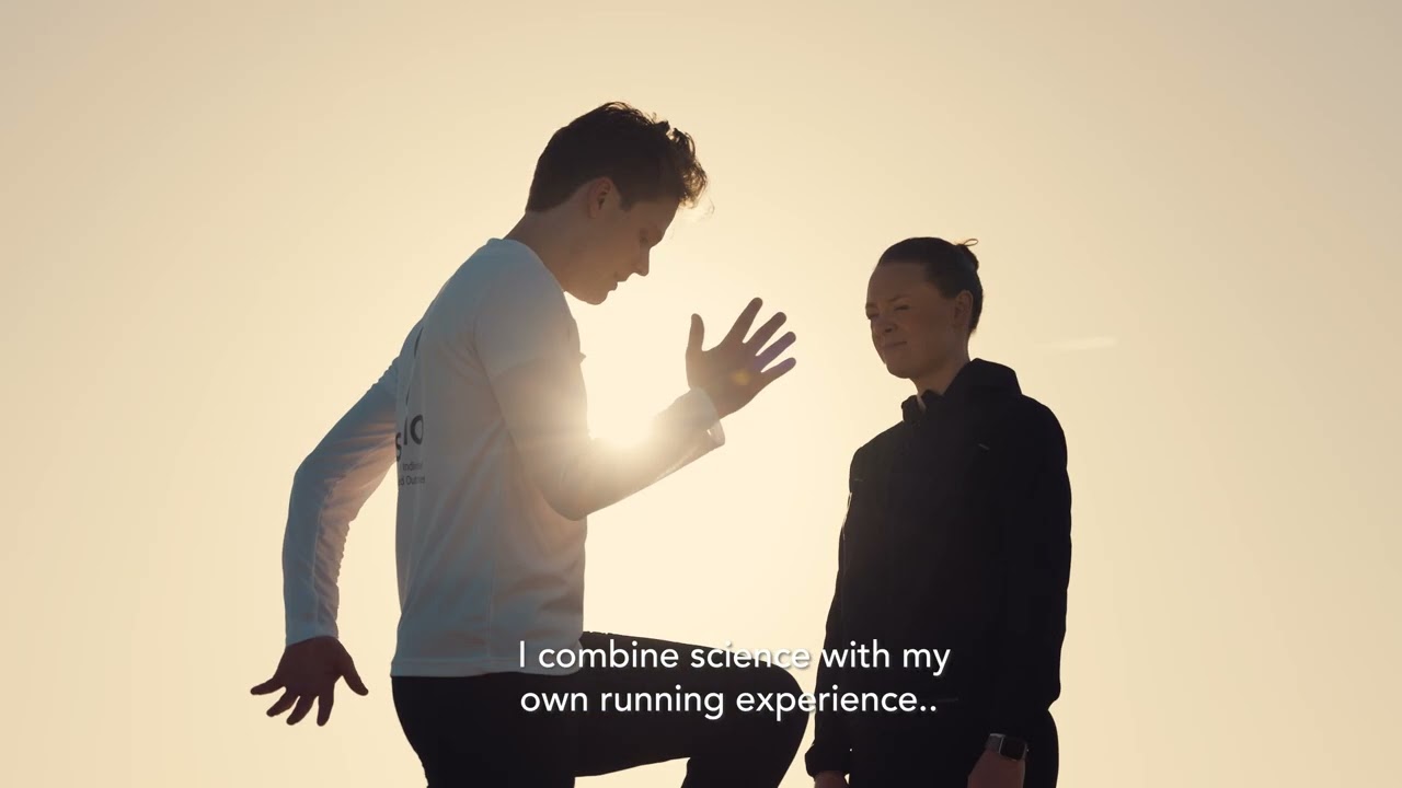 Silhouettes of a man in a white shirt and a woman in a black jacket standing outdoors at sunset, with the caption 'I combine science with my own running experience.'