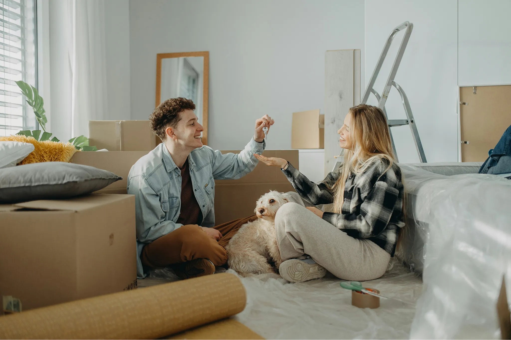 Family of four unpacking moving boxes in a room with cardboard boxes and household items.