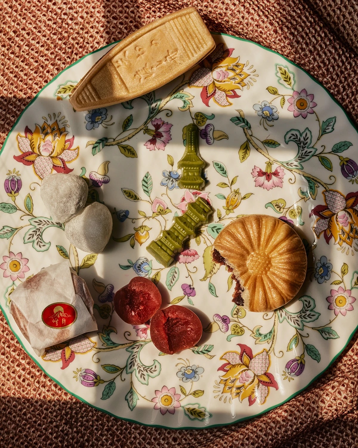 Decorative plate with assorted traditional Japanese sweets including mochi, yokan jelly, and a partially eaten manju.