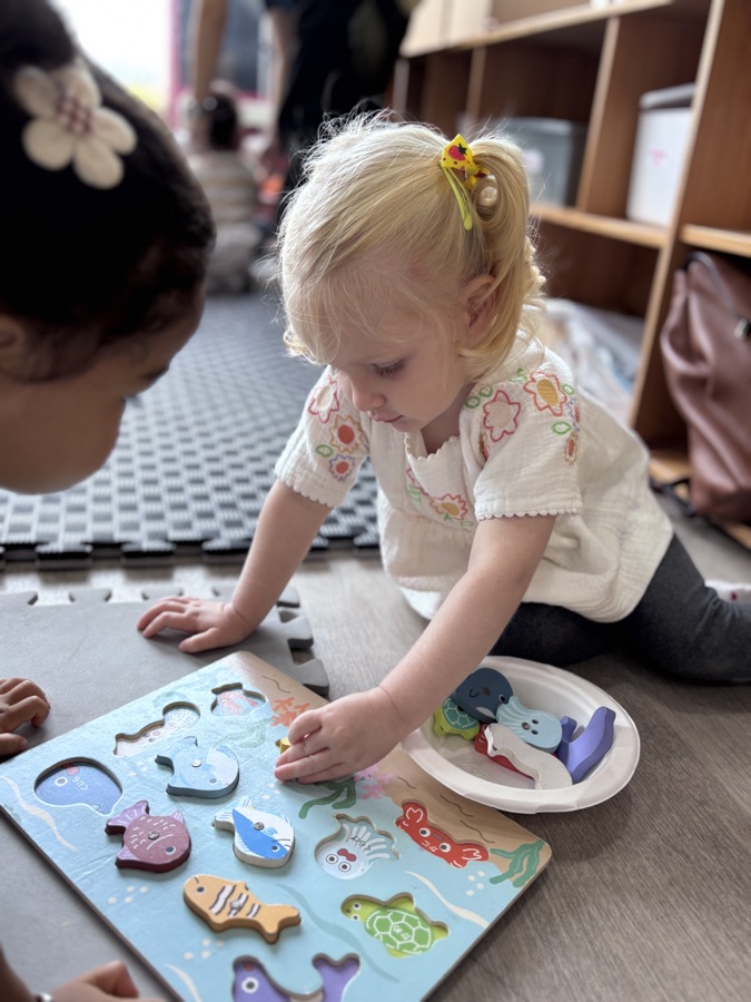 A toddler fitting wooden puzzle pieces.