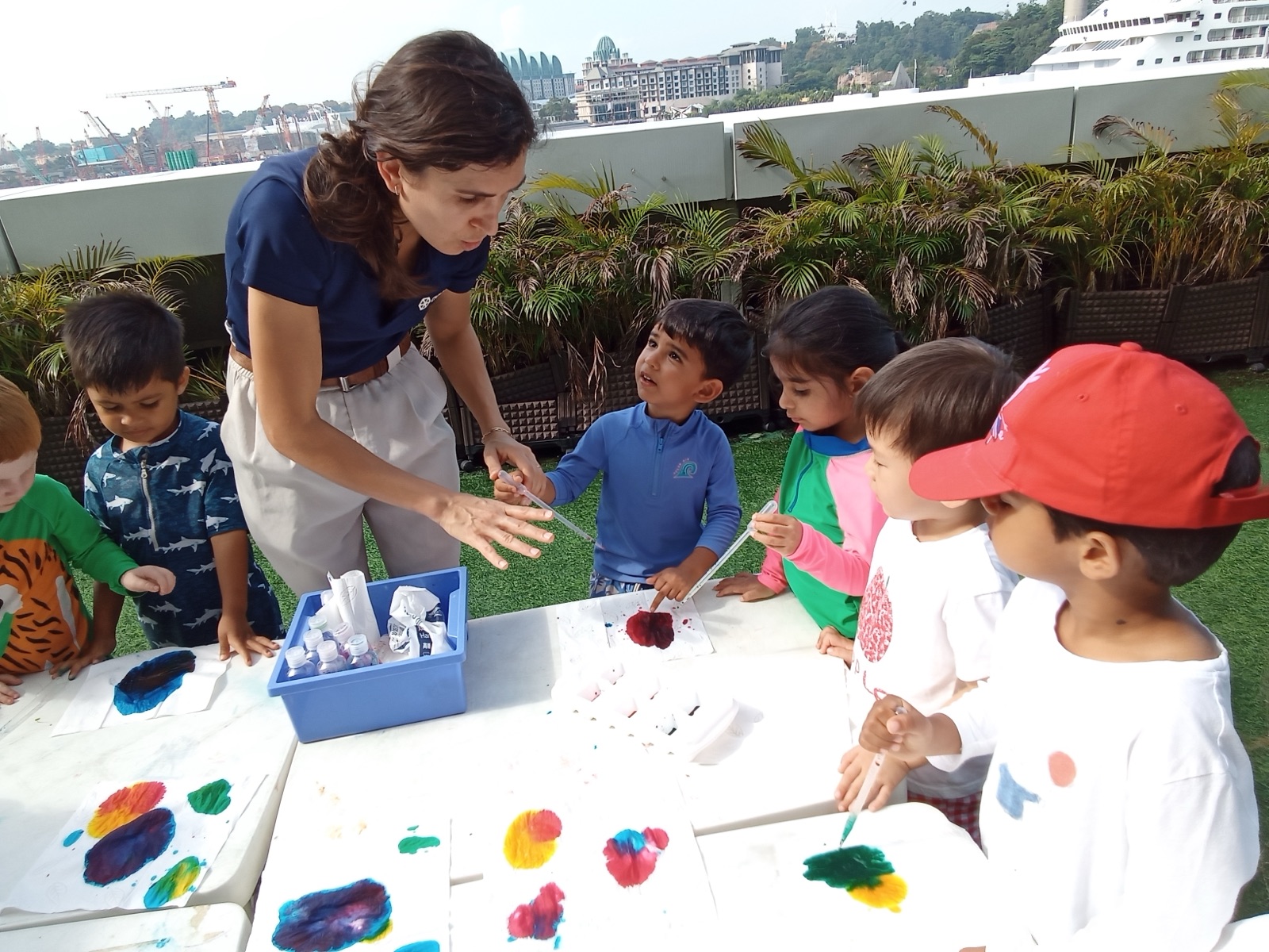 An Agora teacher and preschoolers painting together on the terrace
