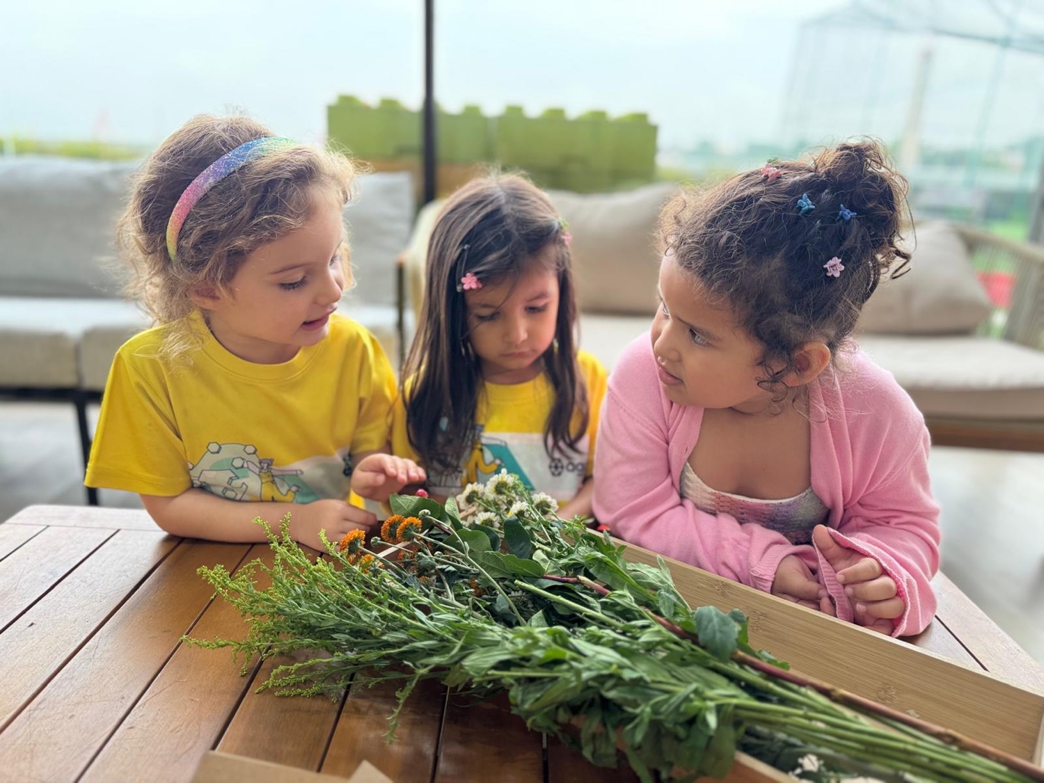 Agora preschoolers in yellow shirts examining wildflowers on the terrace