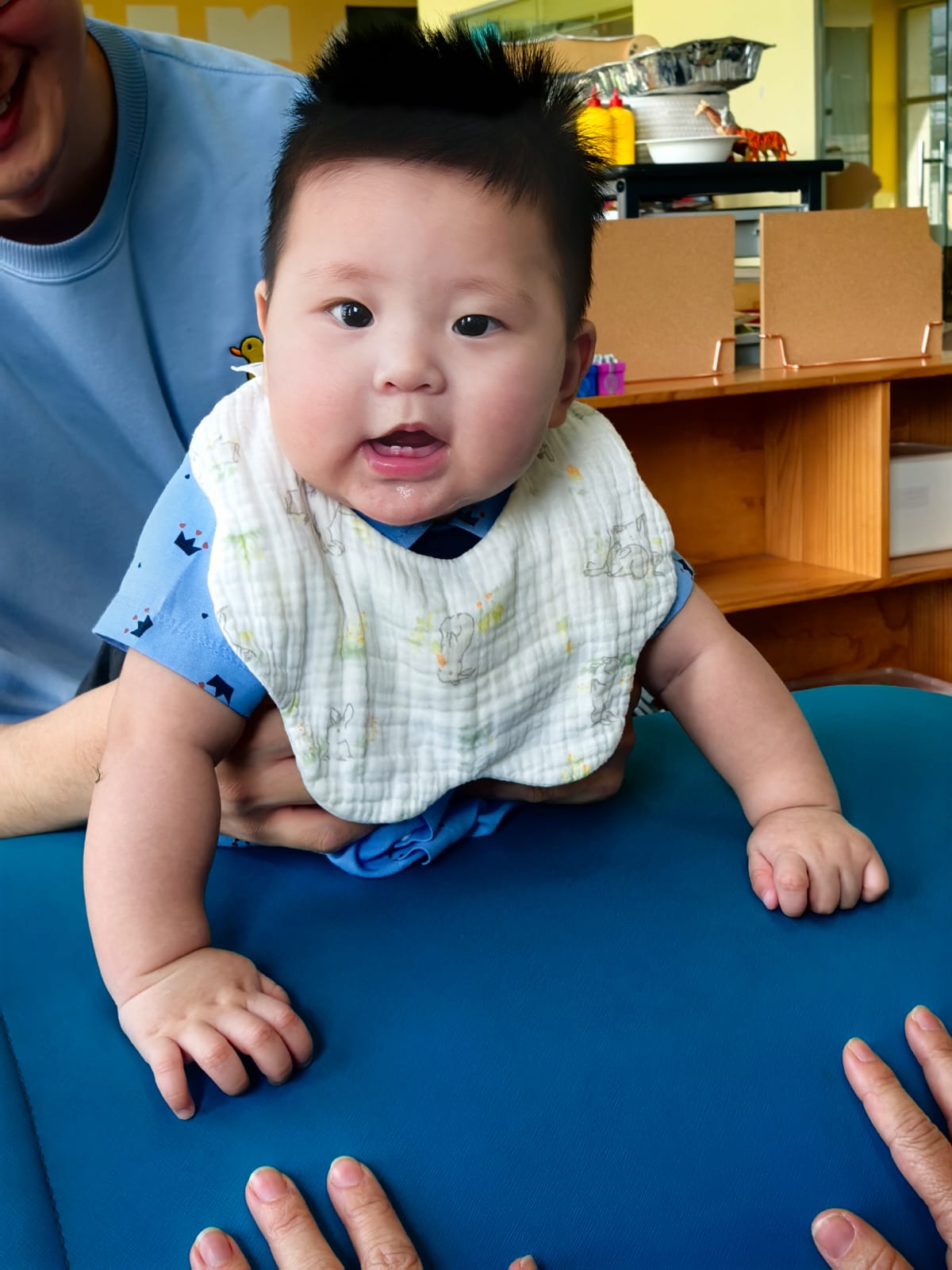 A baby during tummy time supported by a parent