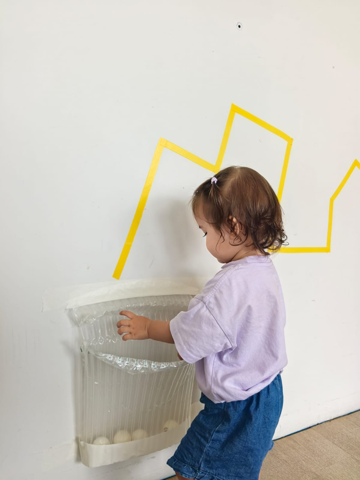 A toddler exploring a textured bubble-wrap panel