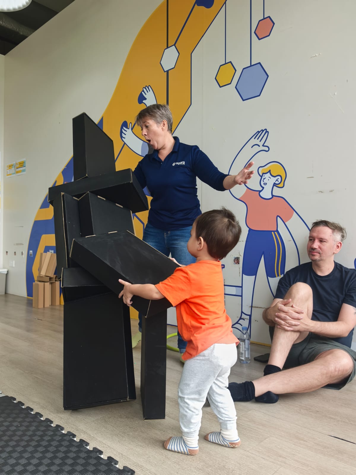 A toddler building a tower with a parent and teacher
