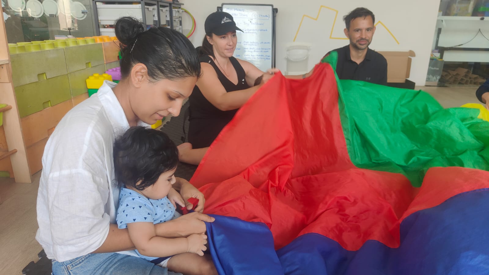 Parents and babies playing under a colourful parachute