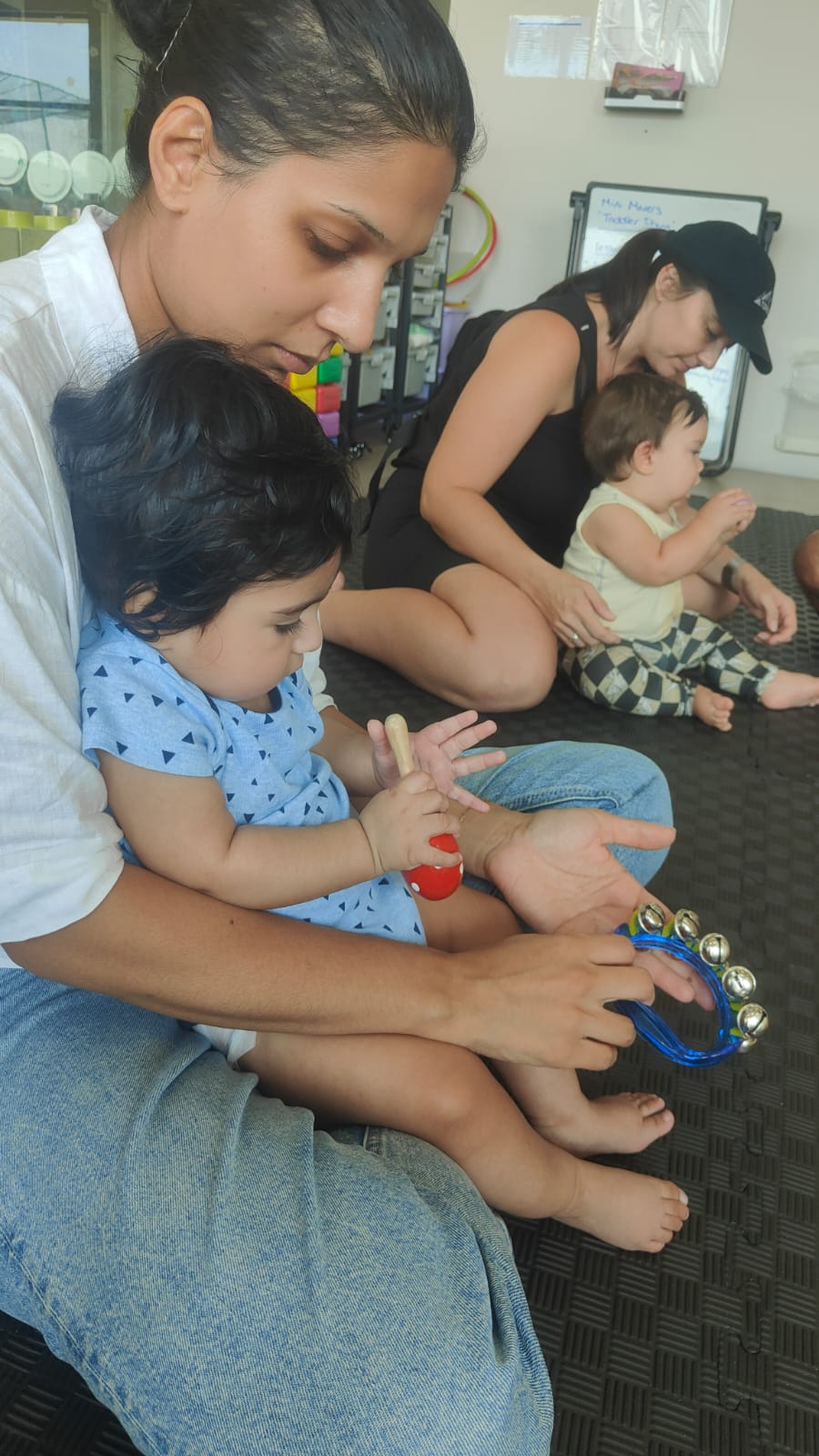 A parent and baby playing a tambourine together