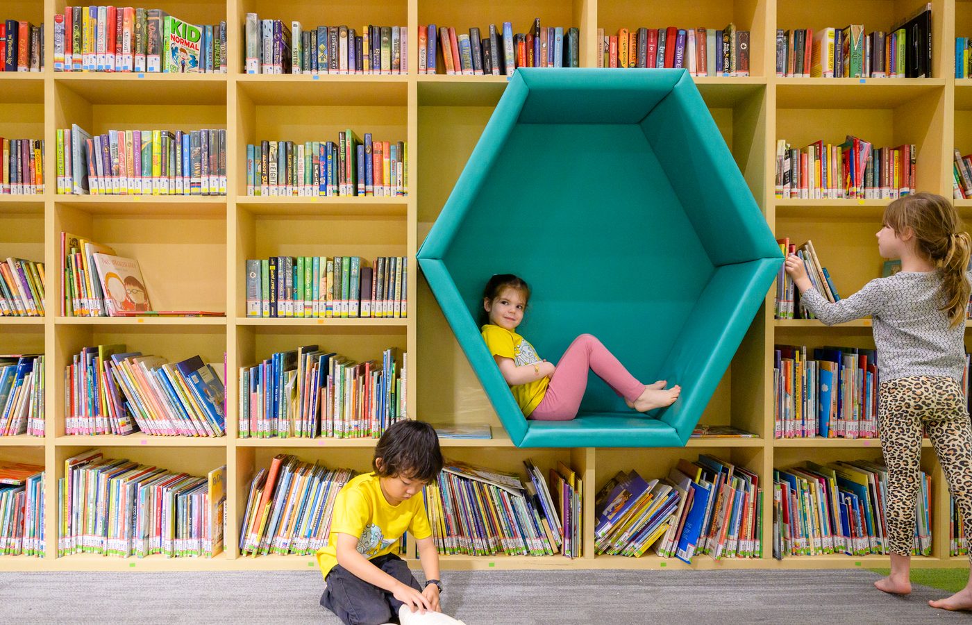 A child reading in a hexagon-shaped nook, while another child reads on the floor below.