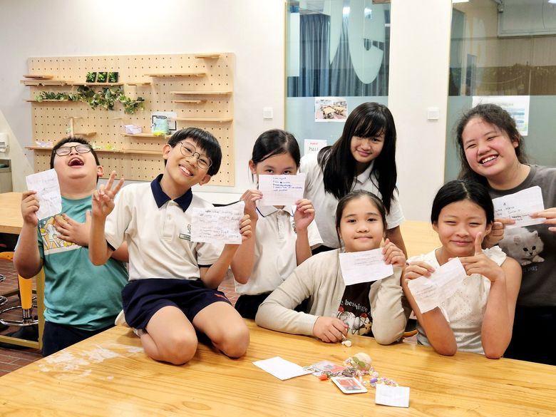Student Care children holding up work they have finished