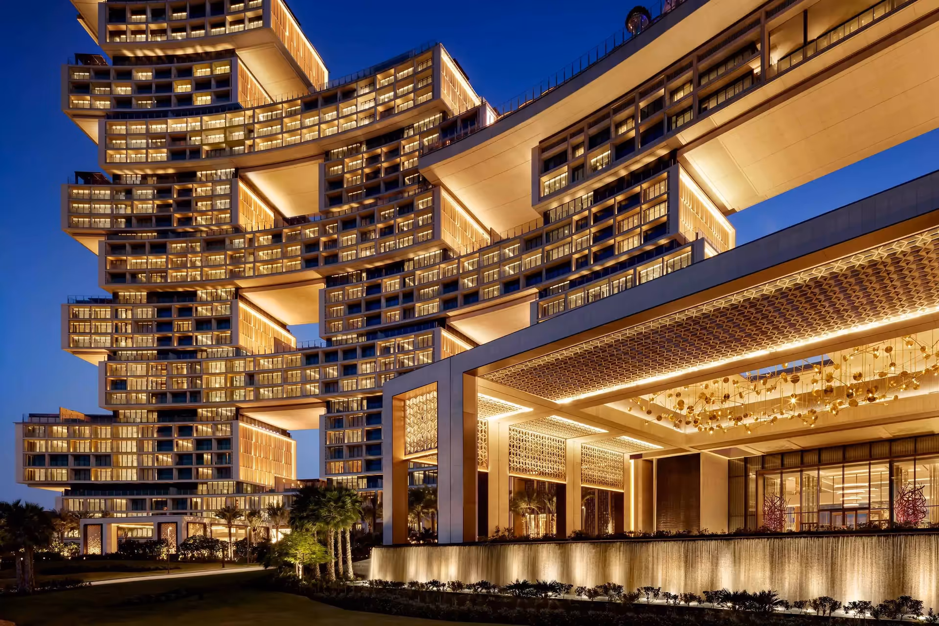 Modern multi-level building with illuminated windows and architectural lighting during twilight.