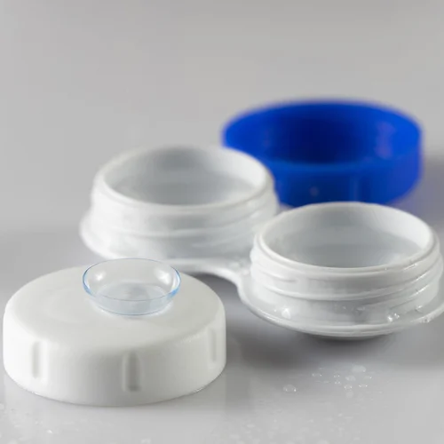 Collection of clear and white plastic cosmetic jars and containers with blue cap displayed on surface.