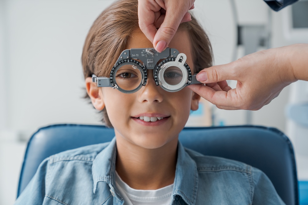 Child wearing optical testing equipment during eye examination at optometrist clinic