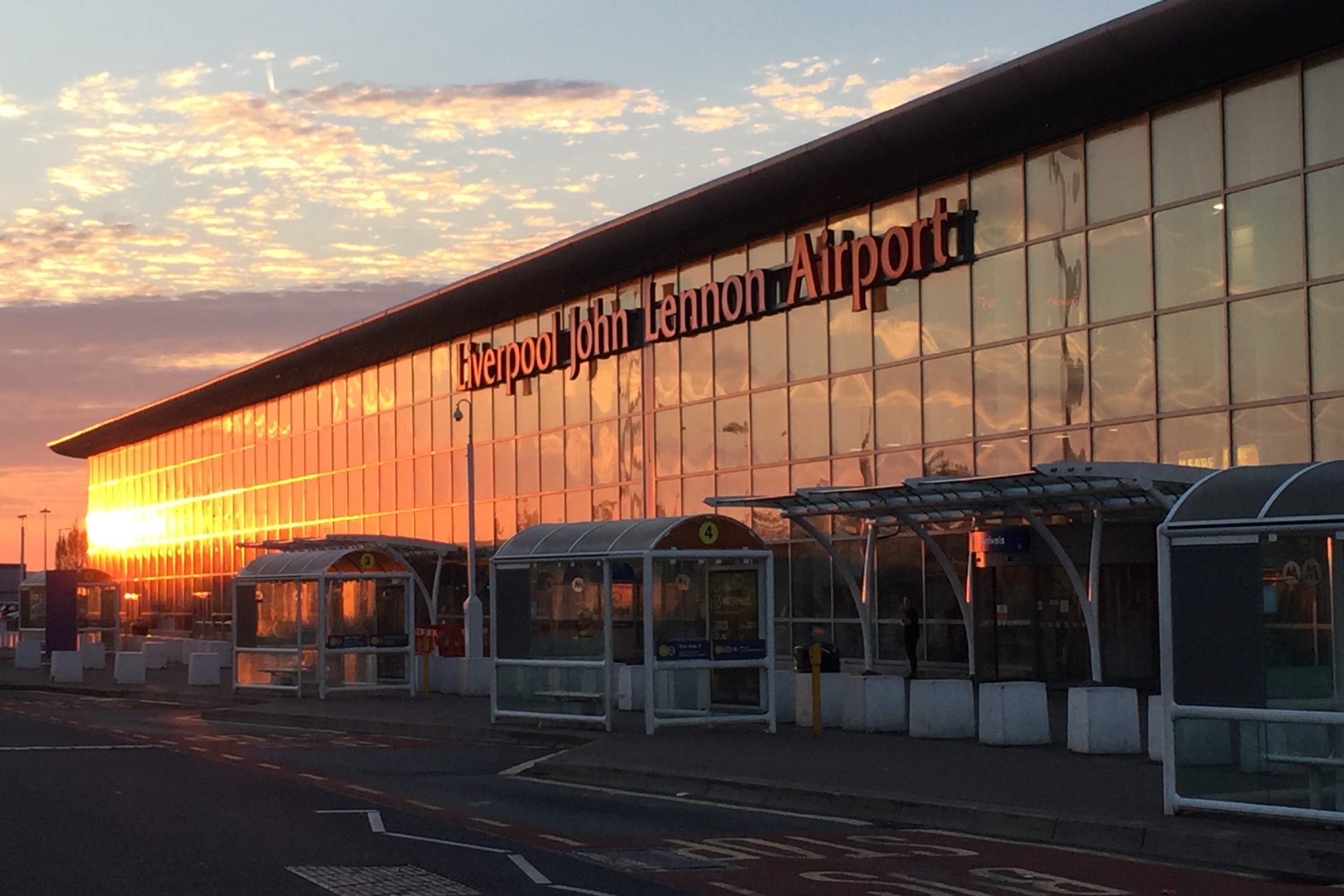 Liverpool John Lennon Airport terminal building reflecting the orange glow of a sunset.