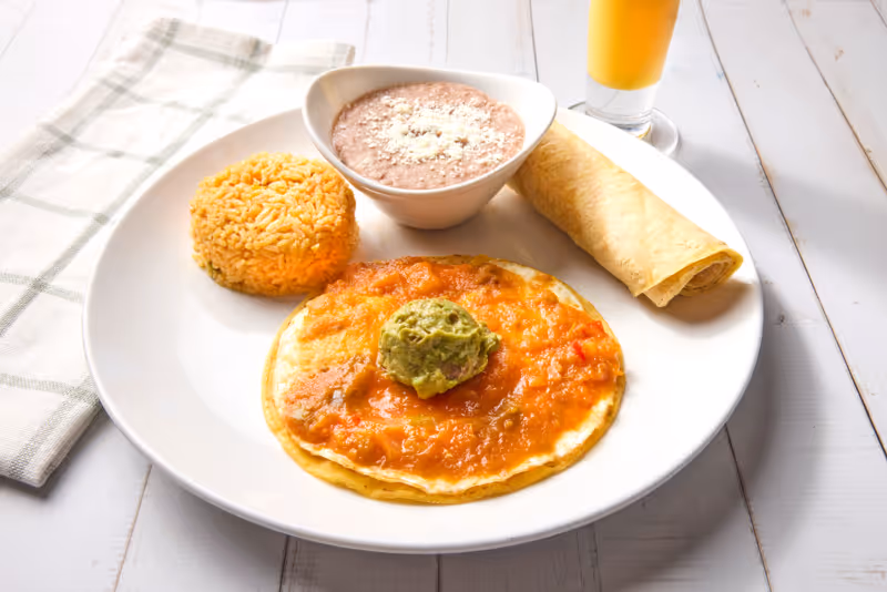 Eggs over-medium with our housemade ranchero sauce on a corn tortilla. Served with Mexican rice, refried beans, and fresh guacamole.