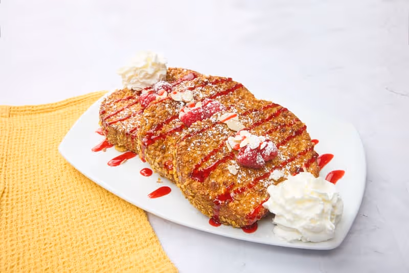 Brioche bread coated in cinnamon and sugar, topped with cream cheese icing, whipped cream, and extra cinnamon.