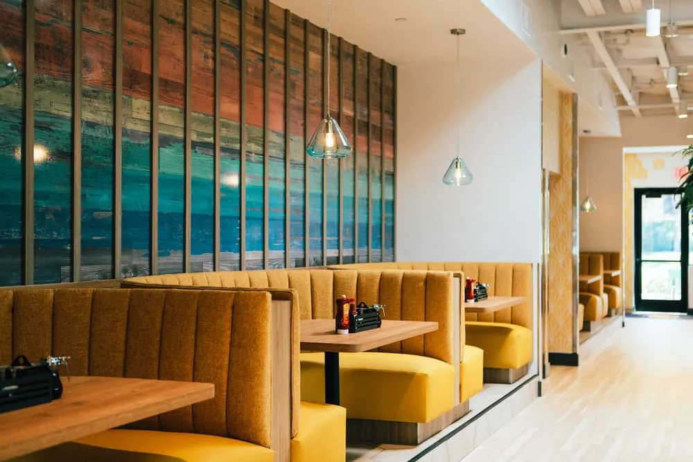 Broken Yolk Cafe Irvine Crossroads interior with teal booths, wood tables, and lush plant decor