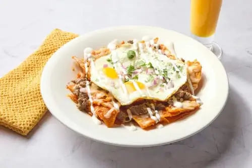 Corn tortilla chips sauteed with red or green sauce, topped with two eggs, Jack cheese, red onion, cilantro and sour cream. Choice of shredded chicken, carne asada, or beef barbacoa.
