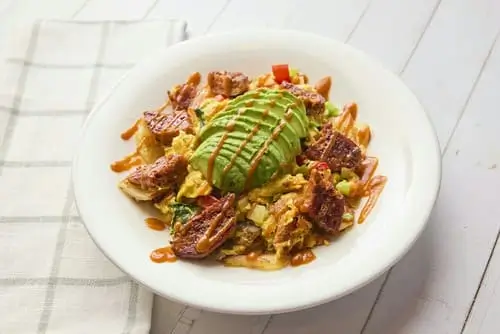 JUST Egg™ scrambled with spinach, mushroom, onion, red and green bell pepper, served over home fries and topped with BEYOND SAUSAGE® hot link, avocado, and sriracha.
