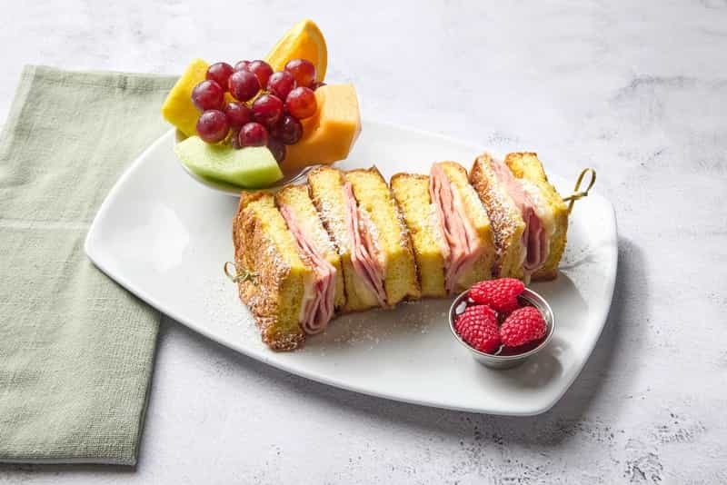 Grilled brioche French toast sandwich with sliced ham and Swiss cheese. Served with raspberry sauce and fresh raspberries.