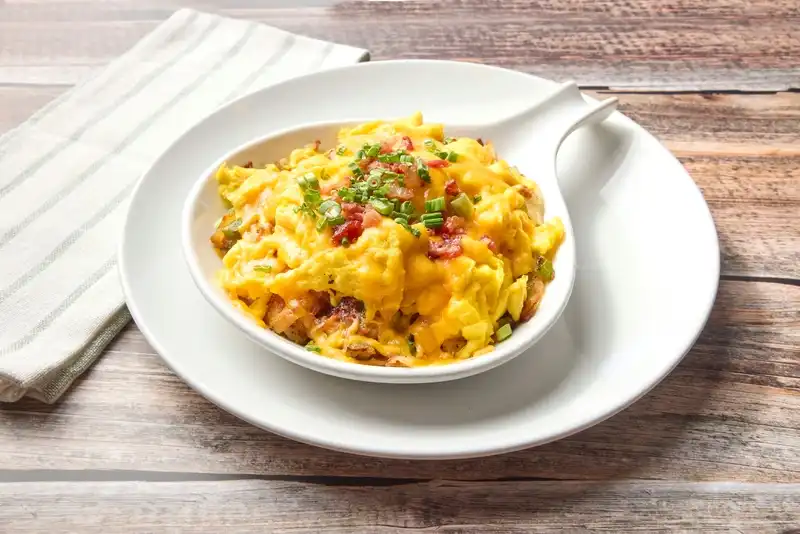 Corned beef hash, bell peppers, onion and home fries topped with scrambled eggs, cheddar cheese, bacon, and green onion.