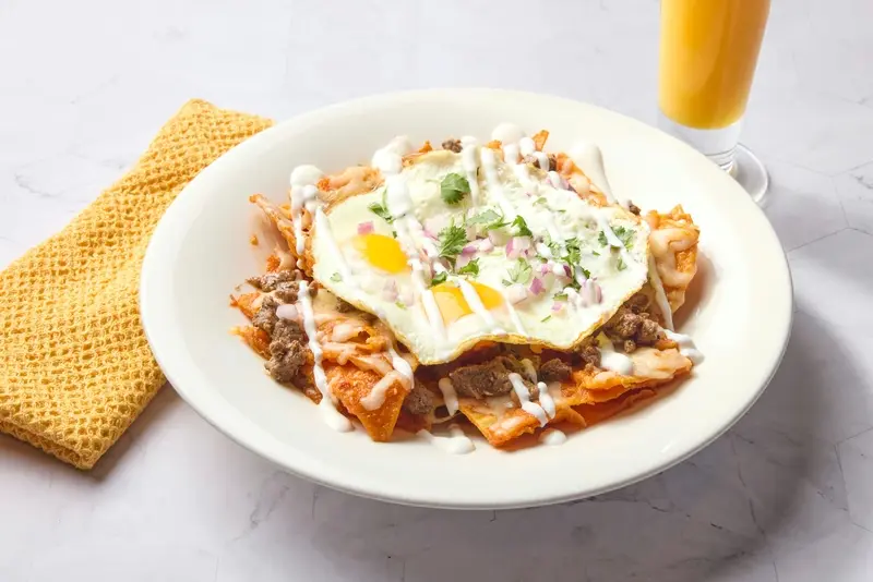 Corn tortilla chips sauteed with red or green sauce, topped with two eggs, Jack cheese, red onion, cilantro and sour cream. Choice of shredded chicken, carne asada, or beef barbacoa.