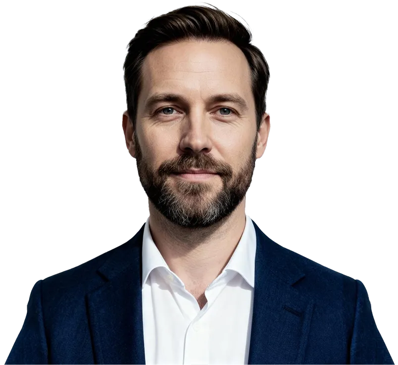 Man with short brown hair and beard wearing a white shirt and dark blue blazer, smiling slightly.