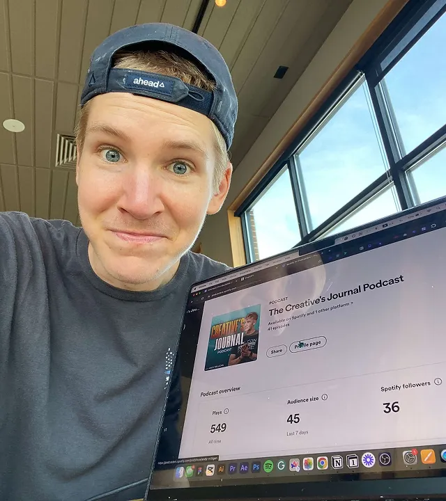 Smiling man wearing a backwards cap holding a laptop showing The Creative's Journal Podcast page with play and follower statistics.