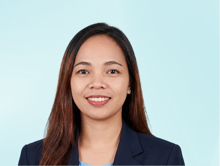 Smiling woman with long dark hair wearing a navy blazer and light blue shirt against a teal background.