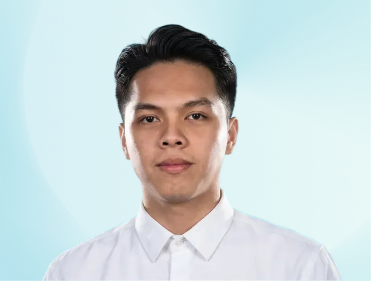 Portrait of a young man with short black hair wearing a white collared shirt against a blue gradient background.