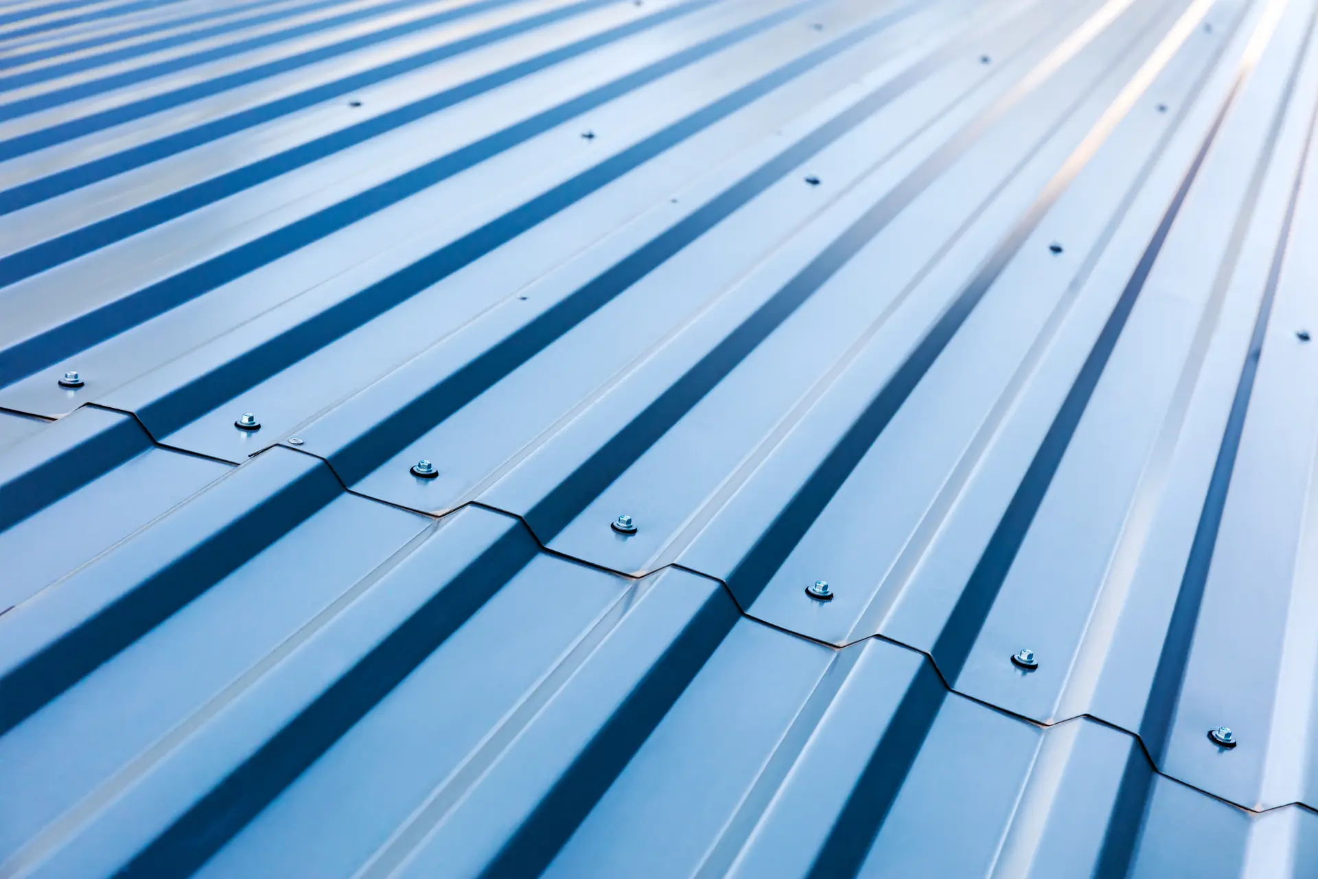 Close-up view of blue corrugated metal roofing sheets with visible screws.