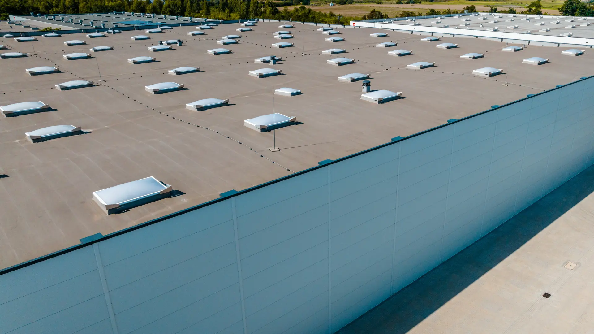 Aerial view of a large industrial warehouse roof with numerous vent skylights.