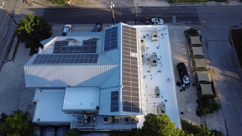Aerial view of a completed AmeriVet commercial reroof in San Antonio, TX by Prism Roof Group — white TPO membrane, standing-seam metal, and rooftop solar.