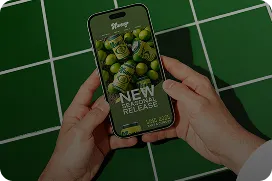 Hands holding a smartphone displaying a new release email campaign on a green tiled background
