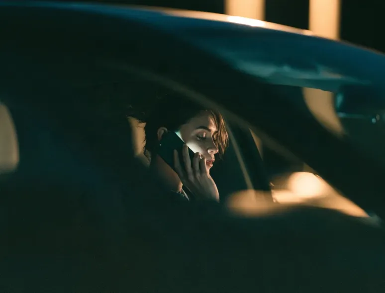 Woman on a phone call in a parked car at night