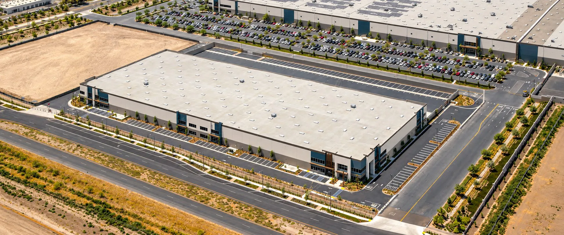 Aerial rendering of a large industrial building with a truck court and parking beside open land