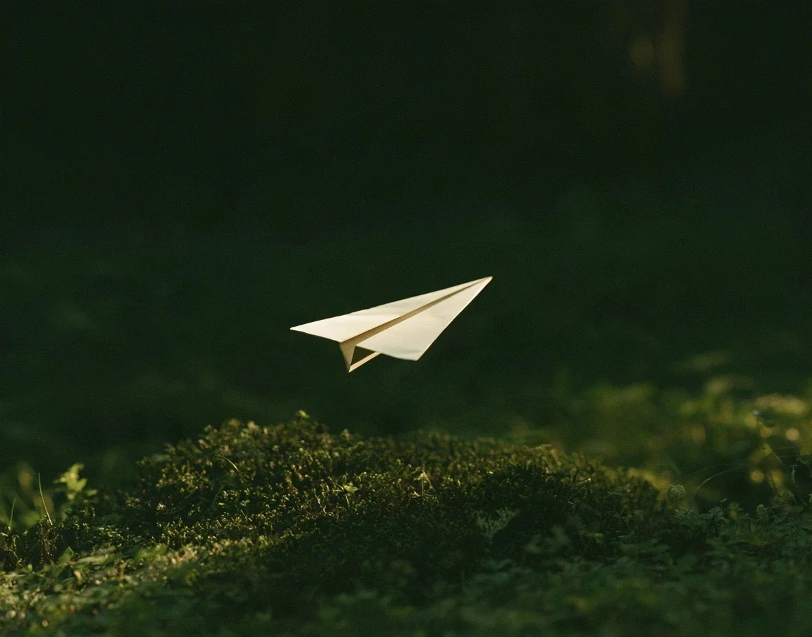 Paper airplane gliding over green moss