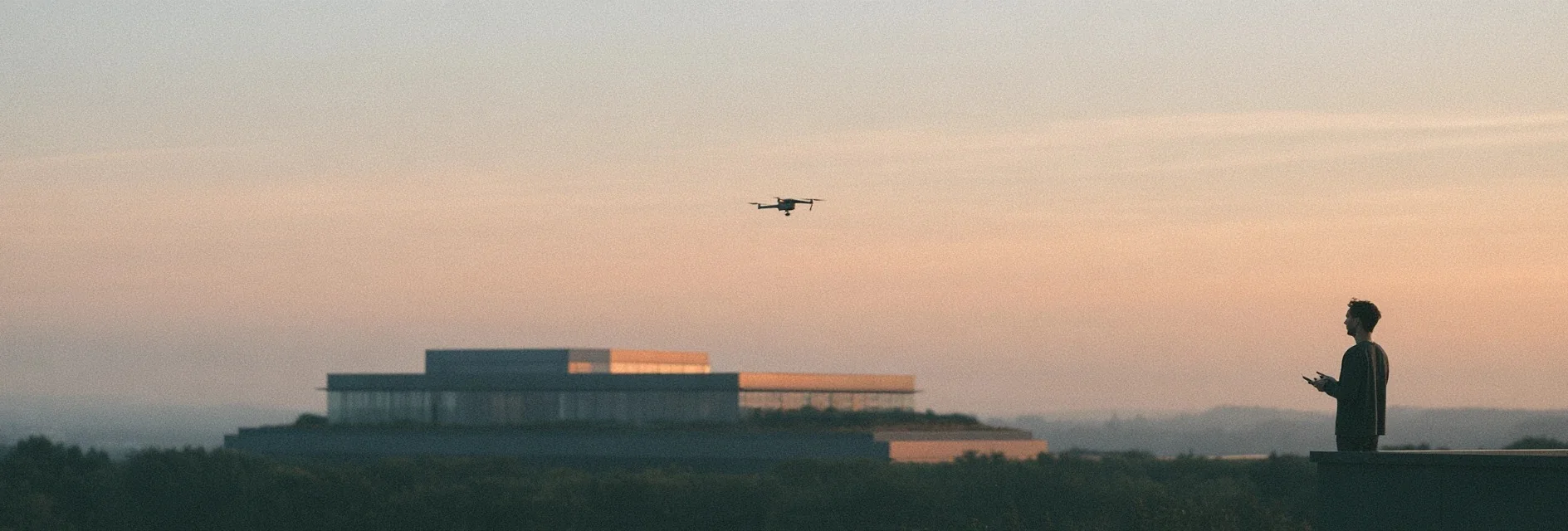 Person flying a drone over a building site at dusk