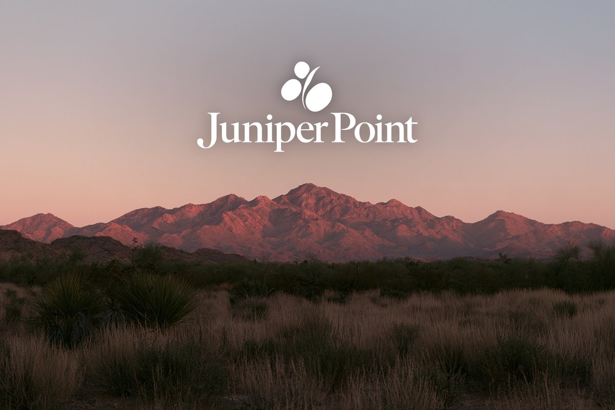 Juniper Point logo over a mountain range at dusk
